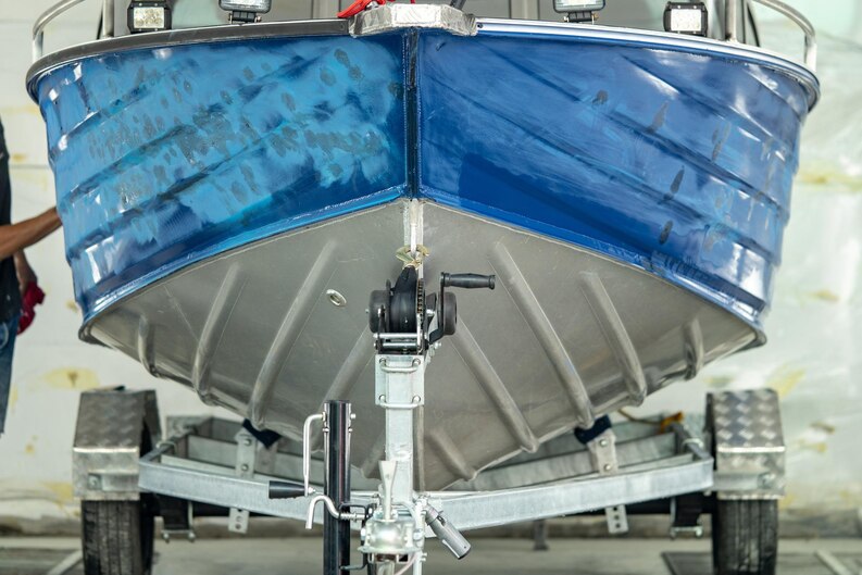 Close-up of a boat on a trailer showing half refinished hull, illustrating gelcoat vs paint surface comparison.